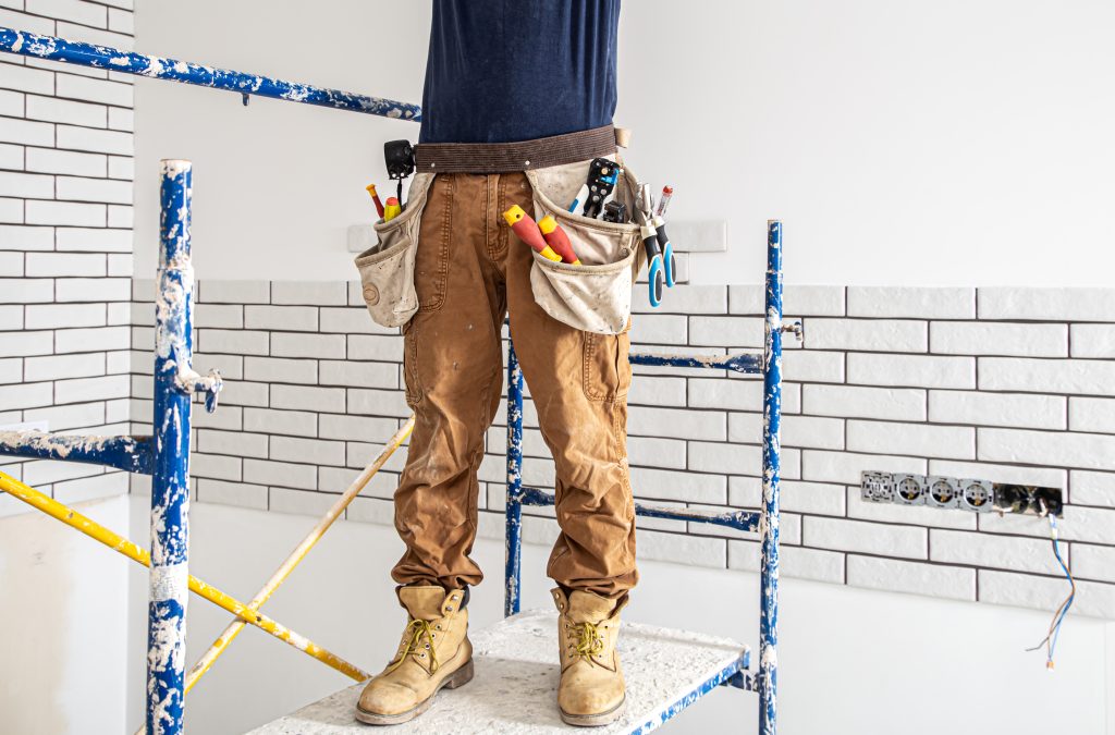 electrician construction worker in work clothes on a stepladder.